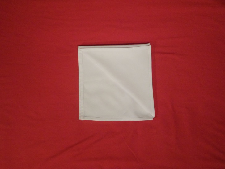 Folding napkins for silverware Step Five find the corner with all four lose corners and fold the top one back on its self to the opposite side. 